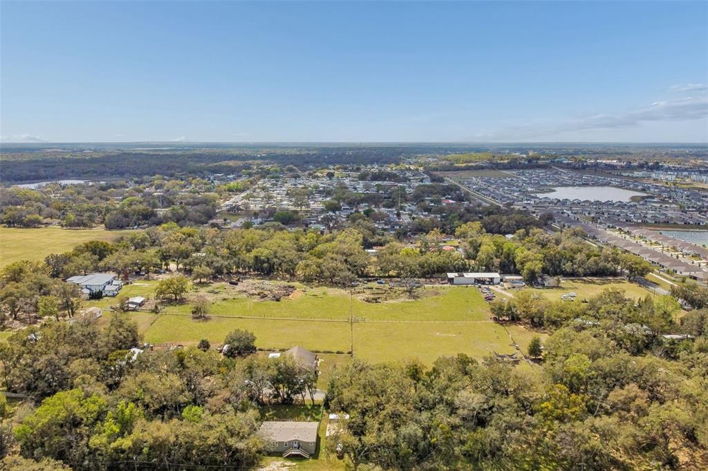 An aerial view shows a large, grassy lot surrounded by trees and residential neighborhoods — 8302 WIRE ROAD, ZEPHYRHILLS, FL