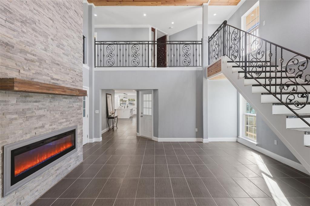 A living room features a stone fireplace, tiled floors, and a staircase with iron railings — 5414 RIVERSIDE DRIVE, PORT ORANGE, FL