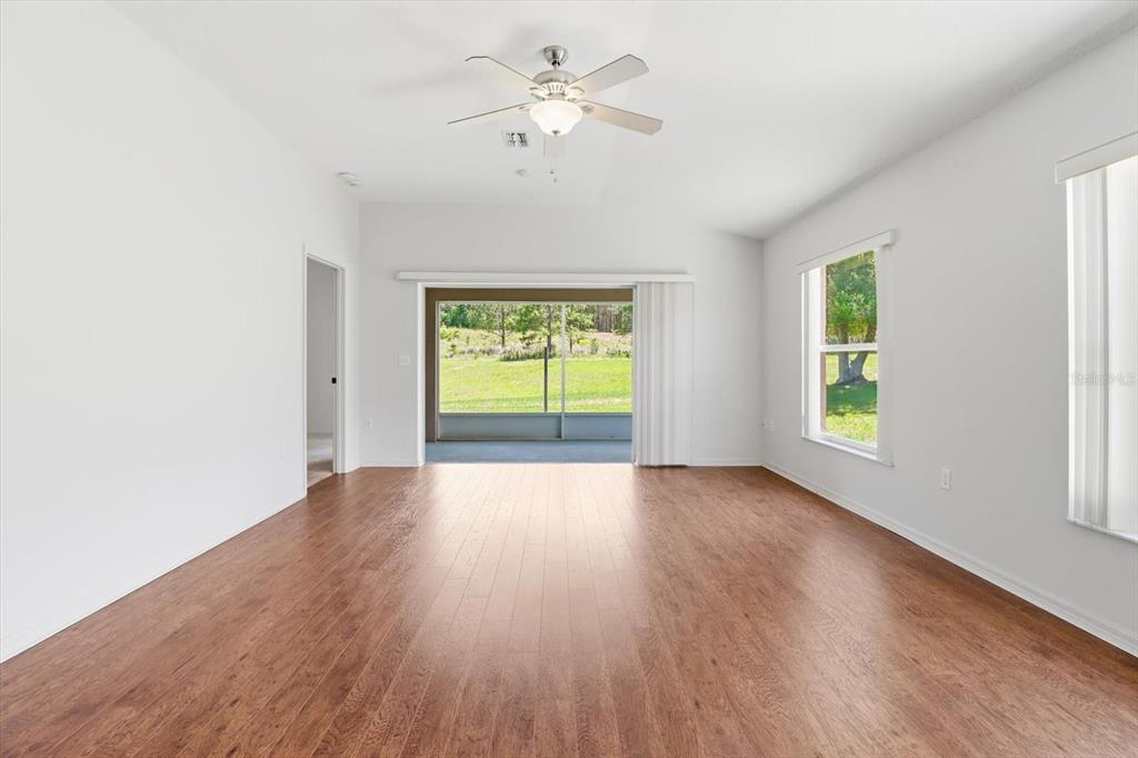 An empty living room with wood-look flooring, a ceiling fan, and a sliding glass door — 826 W COCKATIEL LOOP, HERNANDO, FL