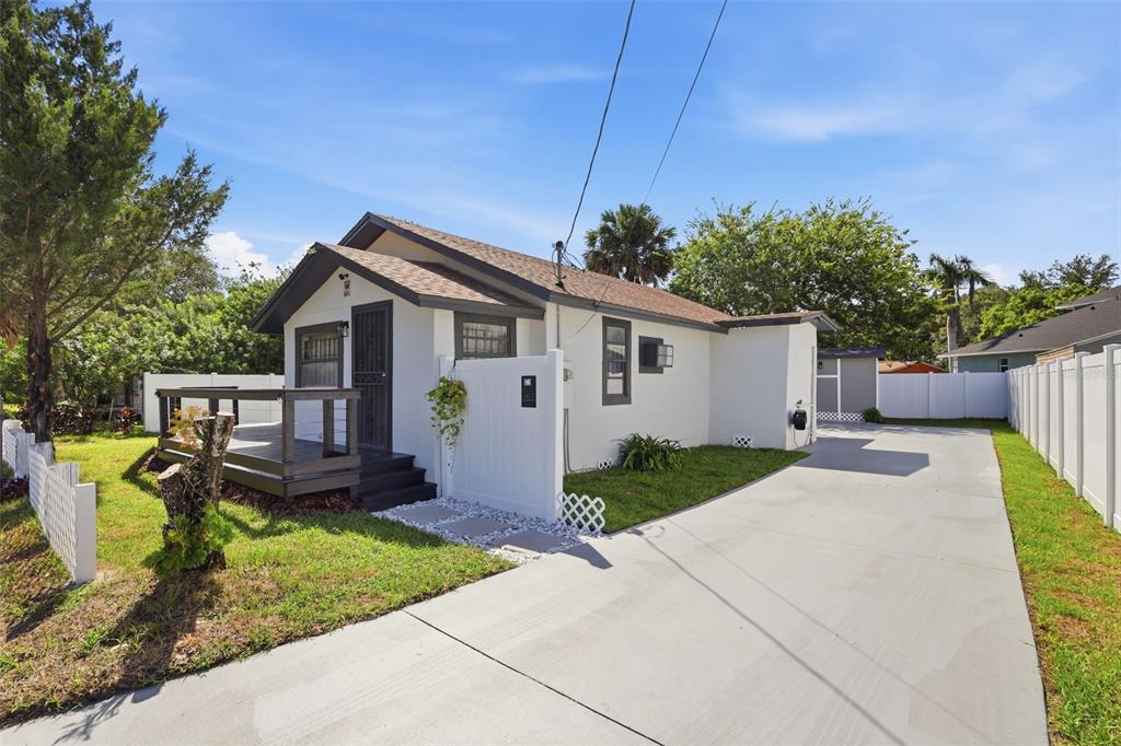 A white house with a dark-trimmed front deck and a long concrete driveway — 1416 SOUTHWEST ROAD, SANFORD, FL
