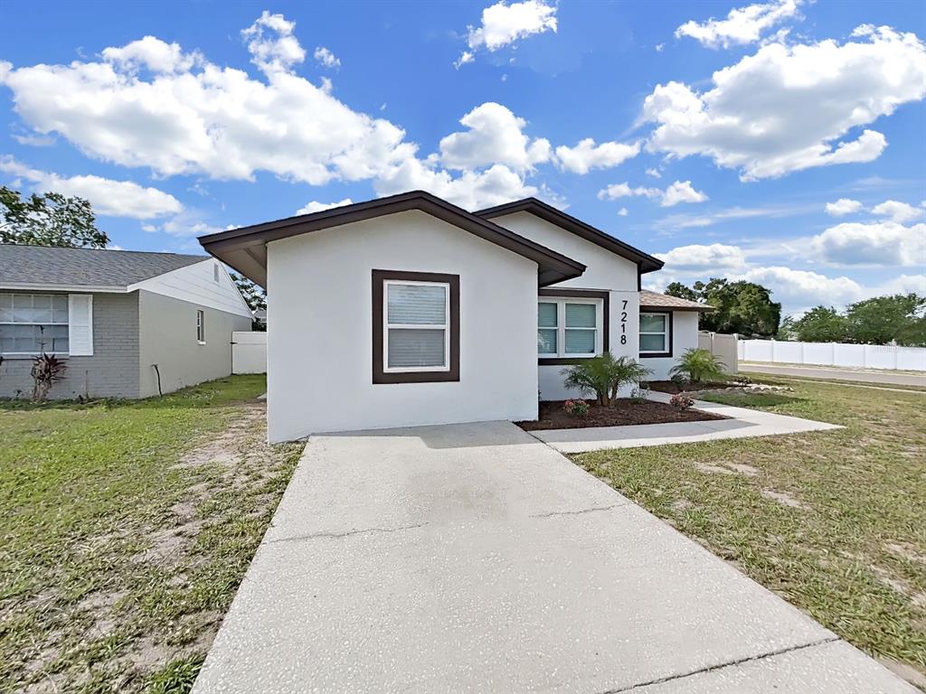 A white single-story house features a concrete driveway and a brown-trimmed window — 7218 LUNITA COURT, TAMPA, FL
