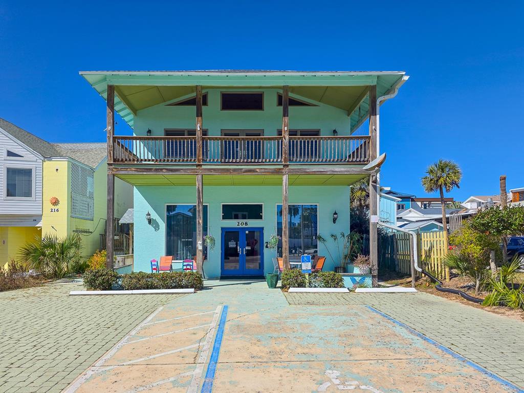 A light green two-story building with a balcony and a paved parking area in front — 208 S 3RD STREET, FLAGLER BEACH, FL