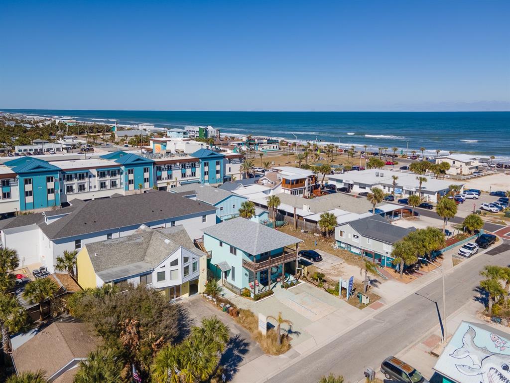 An aerial view shows a coastal neighborhood with houses, a hotel, and the ocean beyond — 208 S 3RD STREET, FLAGLER BEACH, FL