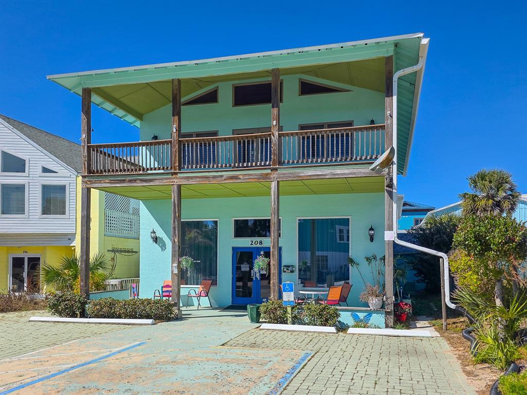 A two-story light green building with a covered balcony and a paved parking area — 208 S 3RD STREET, FLAGLER BEACH, FL