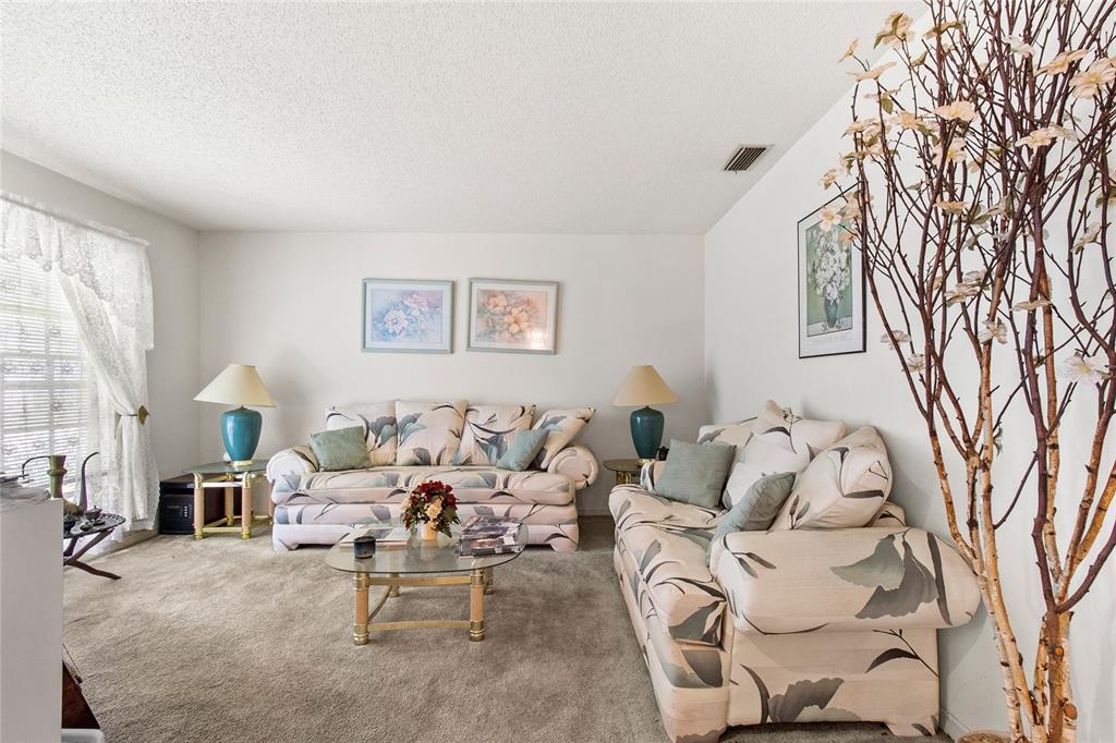 A living room features two floral sofas, a glass coffee table, and a decorative tree — 8657 CROSSBAY DRIVE, ORLANDO, FL