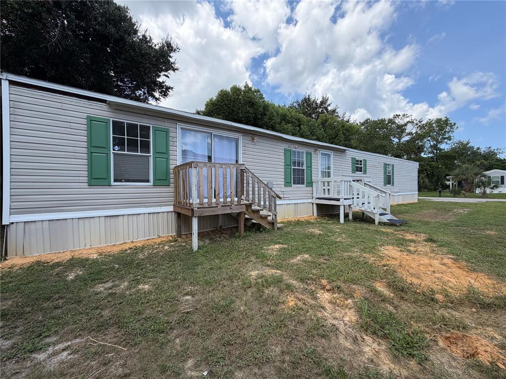 A single-story mobile home with light siding, green shutters, and two wooden entry decks — 1133 AVENUE G, ORMOND BEACH, FL