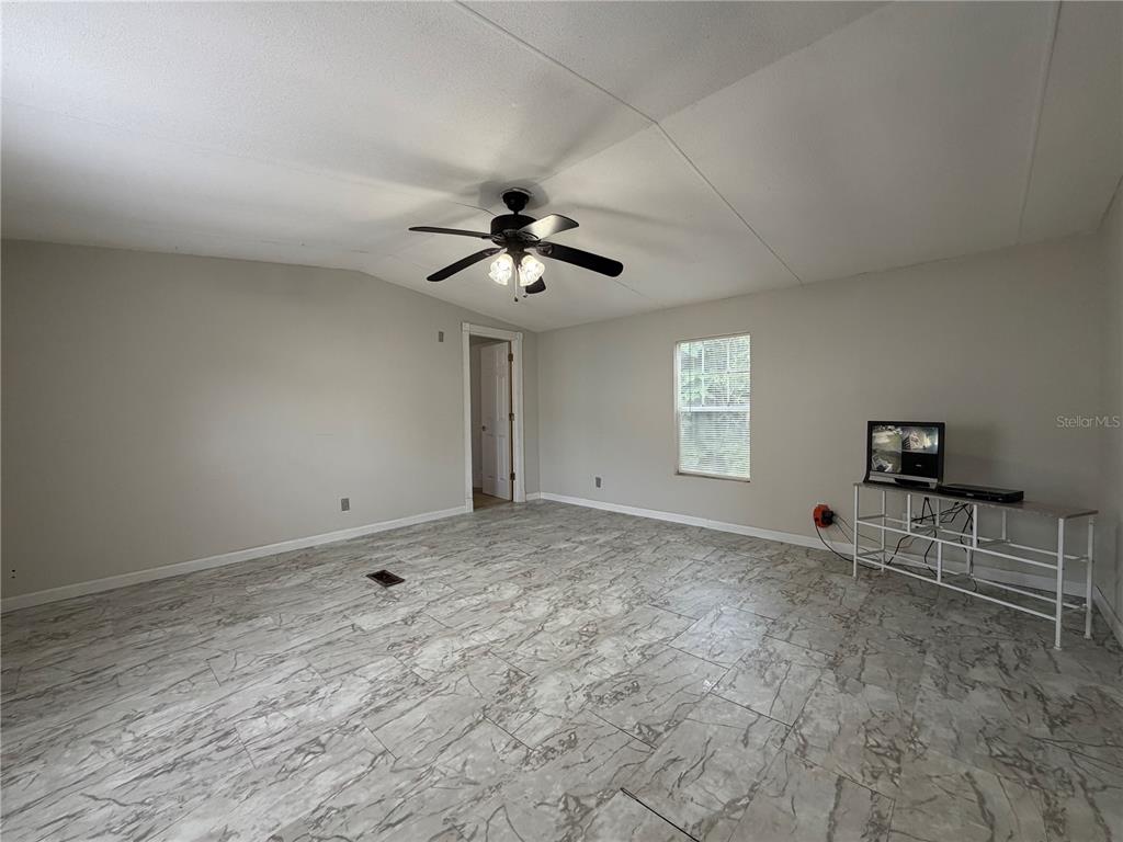 A living room features light gray walls, a ceiling fan, and marble-patterned tile flooring — 1133 AVENUE G, ORMOND BEACH, FL