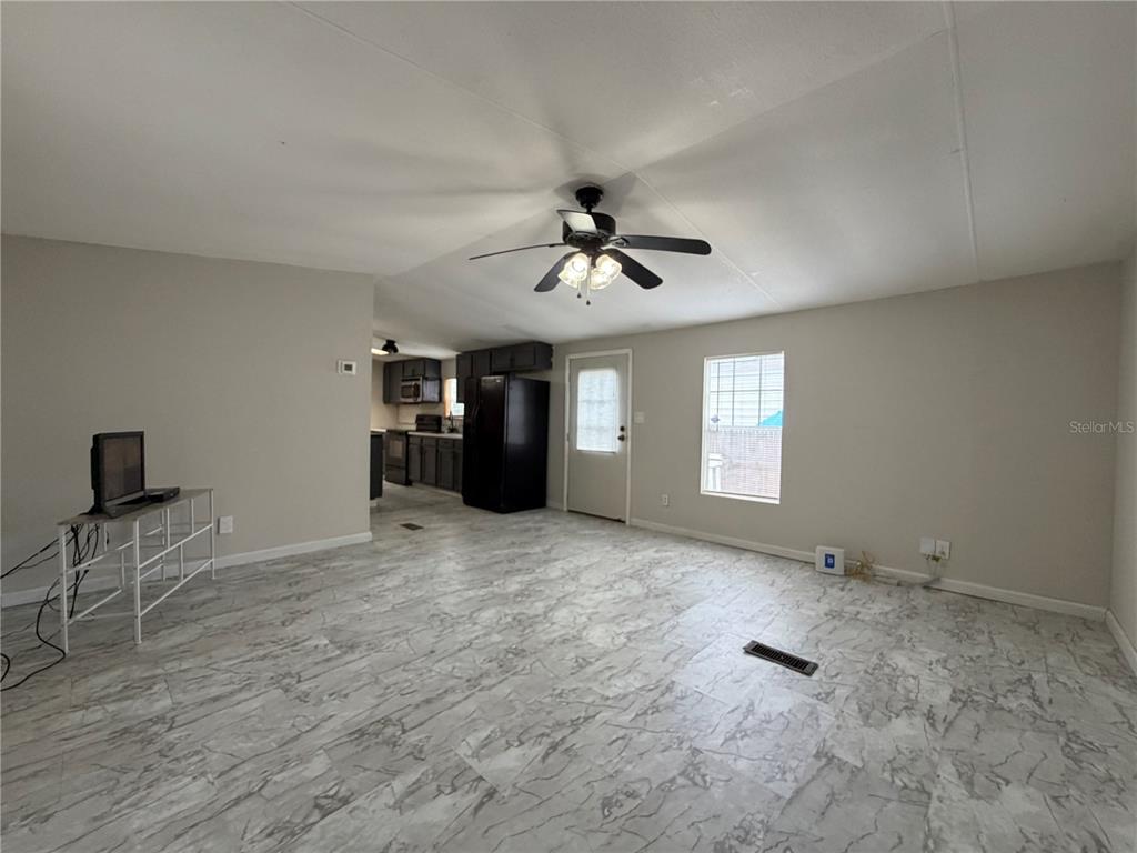 A living room with light gray marble-patterned tile flooring, a ceiling fan, and an open kitchen — 1133 AVENUE G, ORMOND BEACH, FL
