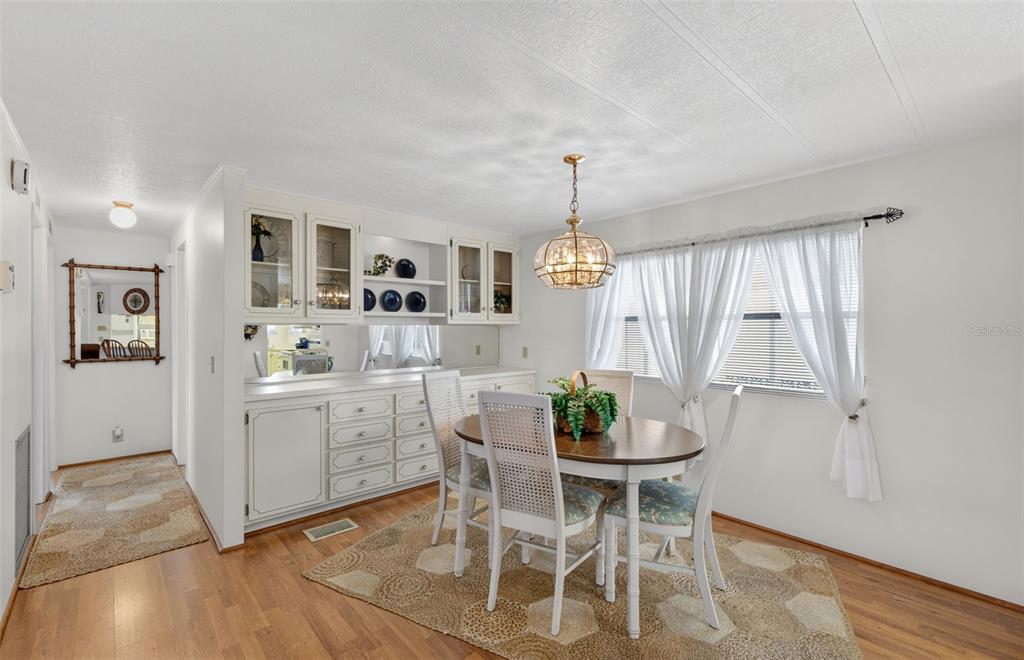 A dining room features a wooden table, white chairs, a hutch, and a chandelier — 322 ROBALO, NORTH PORT, FL