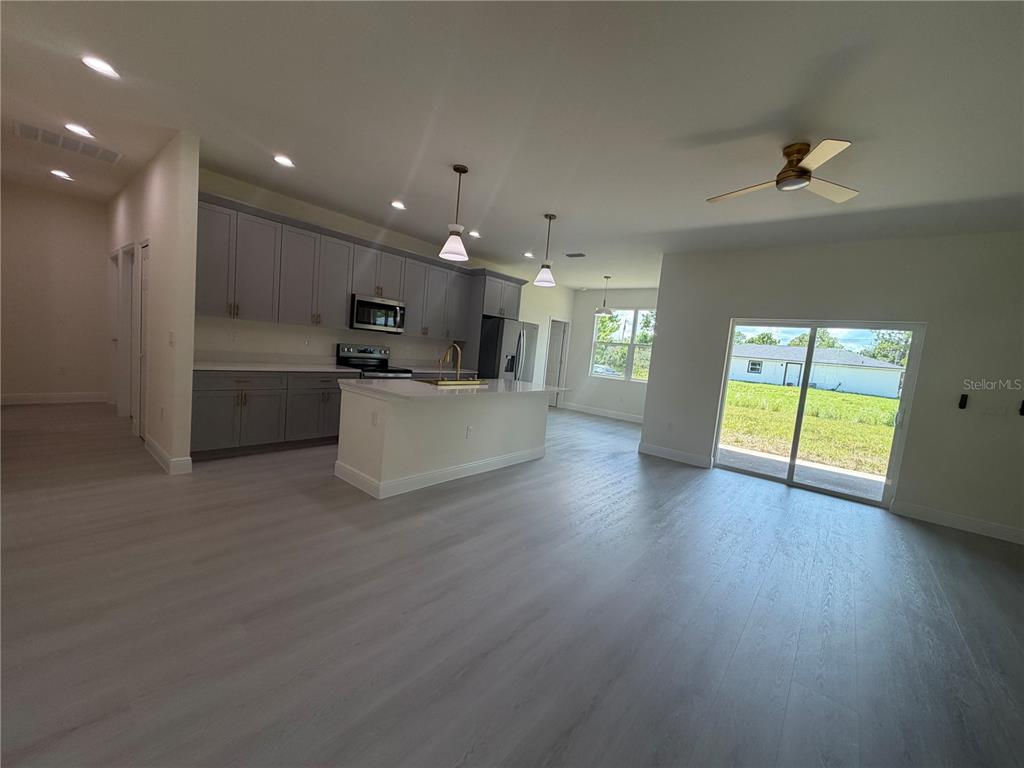 A kitchen with gray cabinets and a white island opens into a spacious living area — 324 CONDOR AVENUE, SEBRING, FL