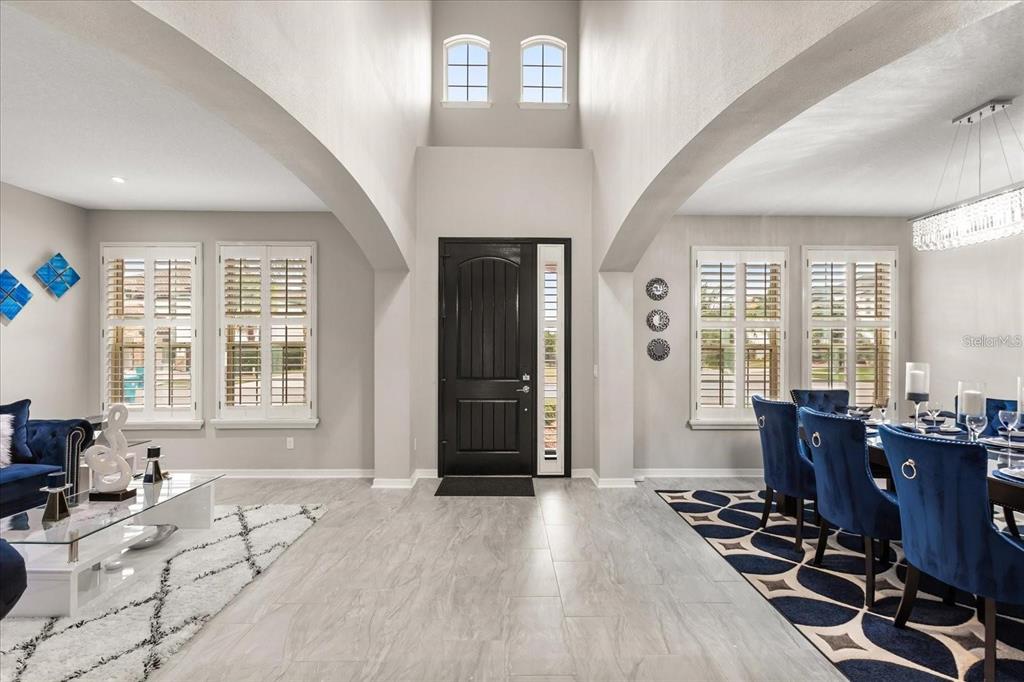 A high-ceilinged entryway features a black front door, tile flooring, and adjacent living and dining areas — 19313 PUMMELO DRIVE, ORLANDO, FL