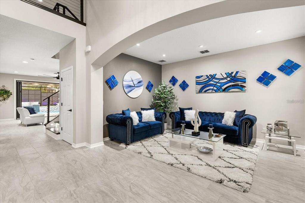 A living room features two blue velvet sofas, a glass coffee table, and blue wall art — 19313 PUMMELO DRIVE, ORLANDO, FL
