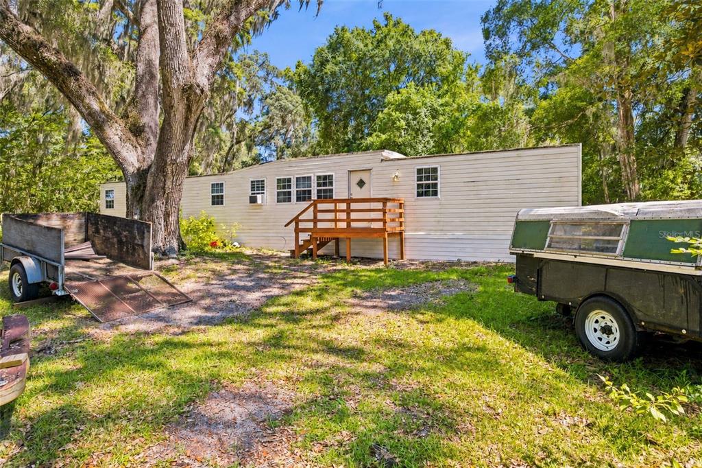 A wooden horse barn stands in a grassy, tree-filled yard under a blue sky — 14000 NE 47TH AVENUE, ANTHONY, FL