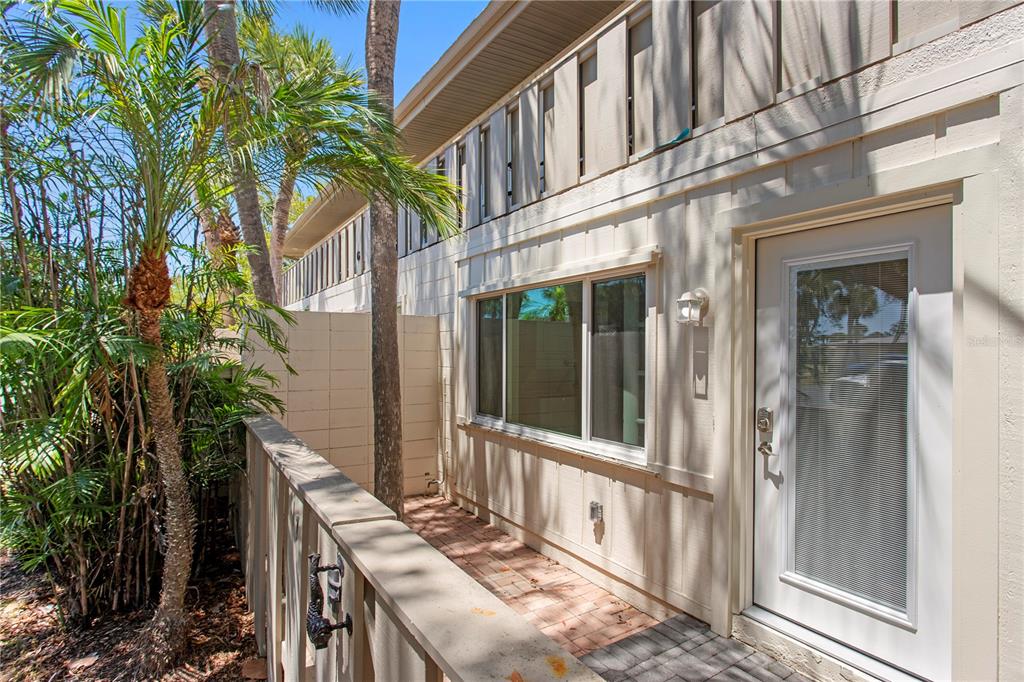 A paved walkway leads to the entrance of a two-story townhouse with a palm tree — 6700 GULF OF MEXICO DRIVE UNIT 117, LONGBOAT KEY, FL