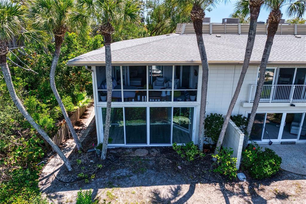 An exterior view of a two-story building with a screened-in balcony and sliding glass doors — 6700 GULF OF MEXICO DRIVE UNIT 117, LONGBOAT KEY, FL