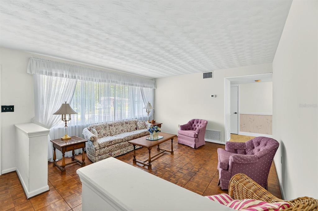 A living room features parquet wood flooring, a floral sofa, and two purple armchairs — 521 S LARRY CIRCLE, BRANDON, FL