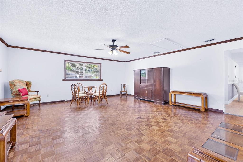 A spacious room features parquet wood flooring, a ceiling fan, and a large wooden hutch — 521 S LARRY CIRCLE, BRANDON, FL