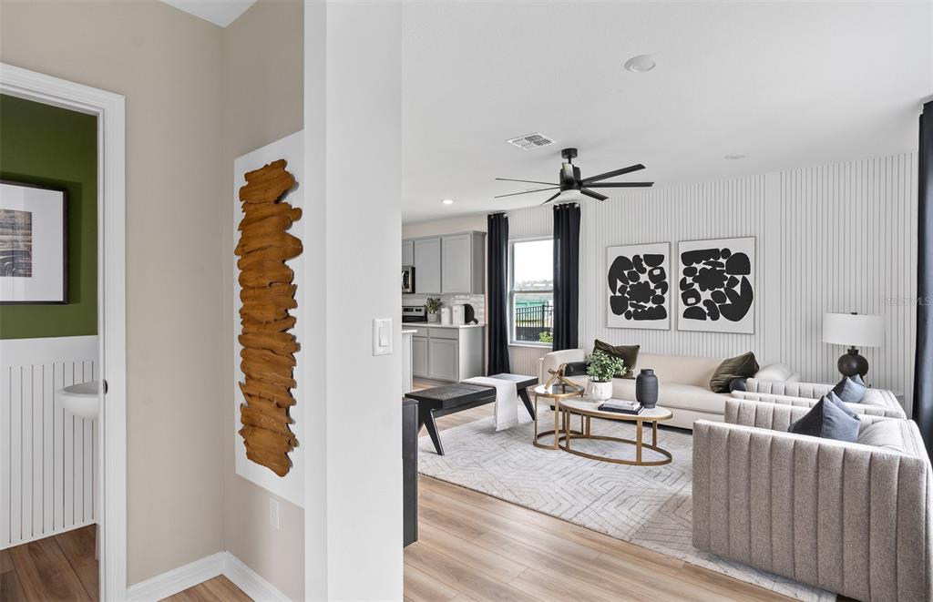 A view from a hallway into a living room with a kitchen in the background — 10927 HEATHER HAVEN STREET, ORLANDO, FL
