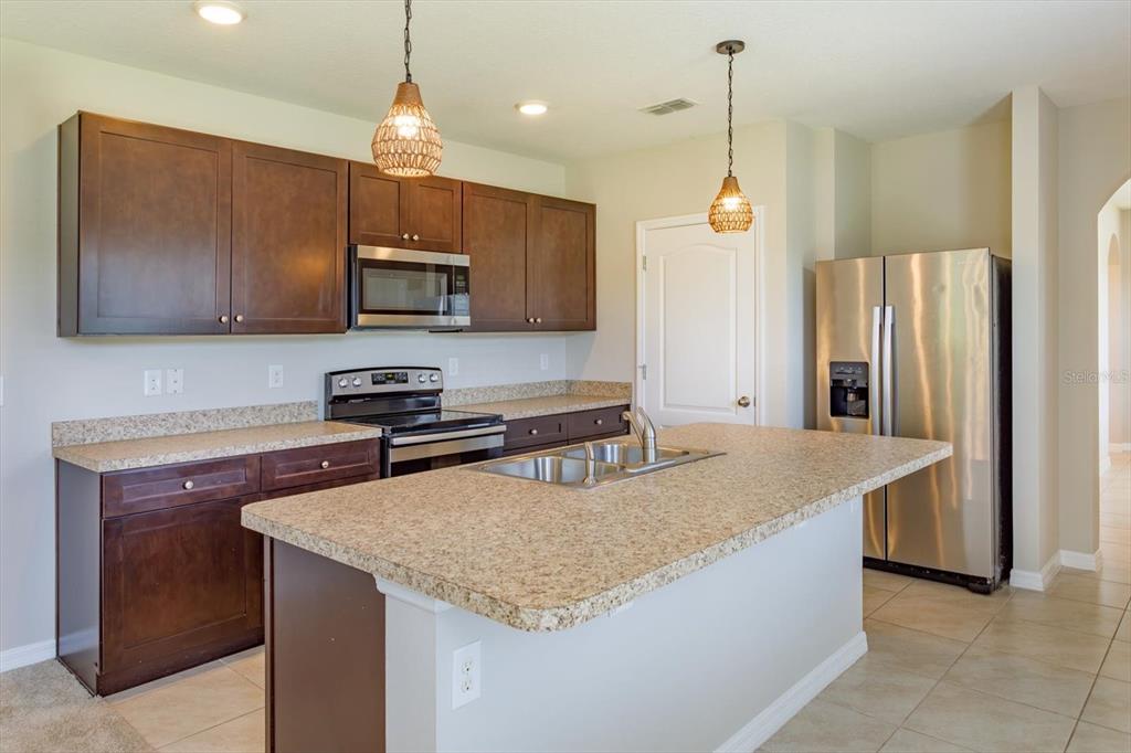 A kitchen features dark wood cabinets, granite countertops, stainless steel appliances, and a central island — 3075 GIBRALTAR BOULEVARD, NEW SMYRNA BEACH, FL