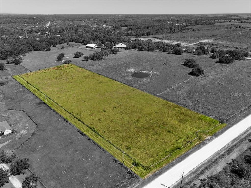 An aerial view shows a rectangular, grass-covered lot bordered by a road and fencing — 39605 TAYLOR ROAD, MYAKKA CITY, FL