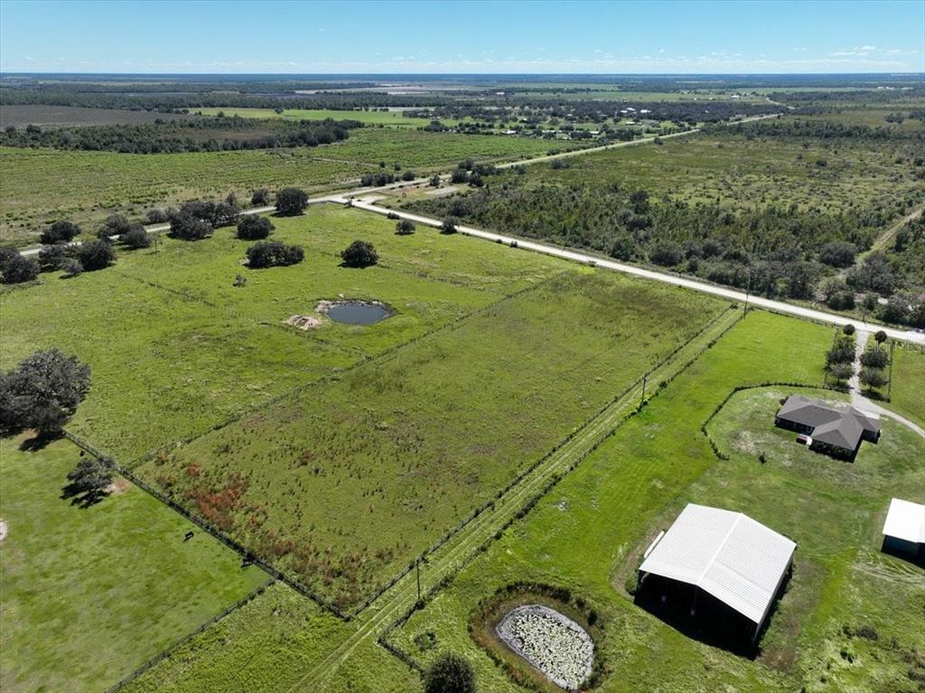 An aerial view shows a large grassy field with two ponds and nearby rural buildings — 39605 TAYLOR ROAD, MYAKKA CITY, FL