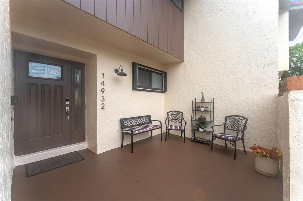 A covered patio features a brown door, a bench, two chairs, and a metal shelf — 14932 SW 89TH ST, MIAMI, FL