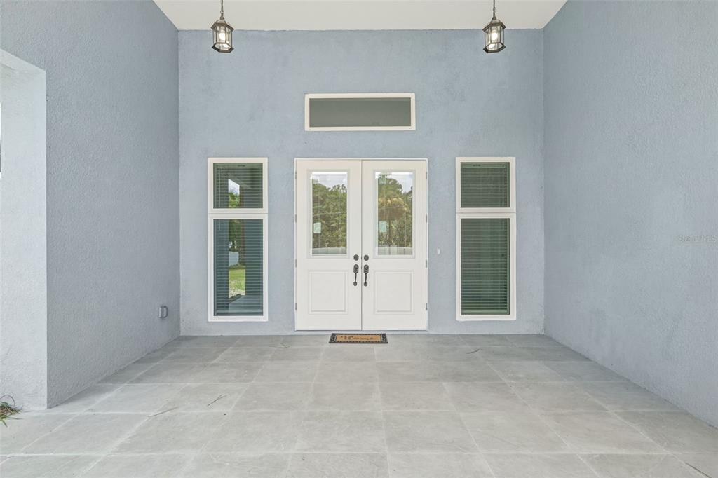 A covered entryway features a double front door, two side windows, and gray tile flooring — 1853 DELLA DRIVE, NAPLES, FL