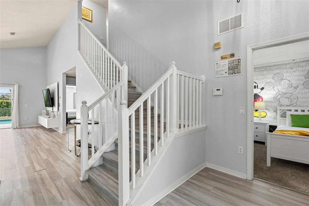 A staircase with white railings sits in a living area next to a themed bedroom — 17845 WOODCREST WAY, CLERMONT, FL