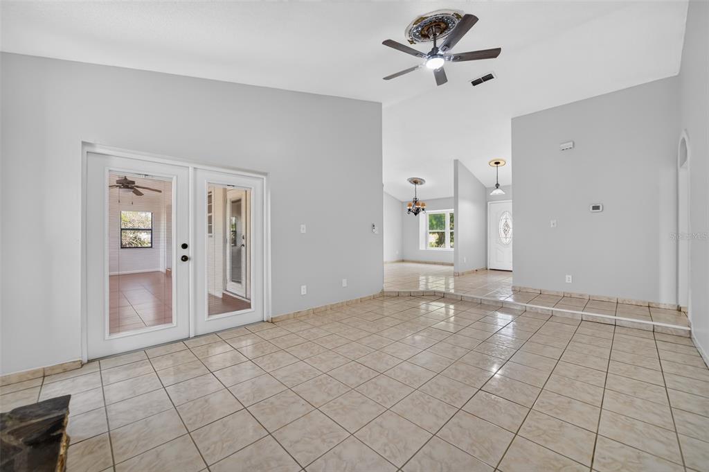 A tiled living room features a vaulted ceiling, a ceiling fan, and double glass doors — 1224 ANDES DR, WINTER SPRINGS, FL