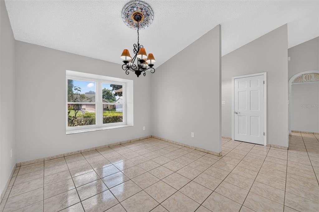 A dining room with light tile flooring, a chandelier, and a window overlooking a yard — 1224 ANDES DR, WINTER SPRINGS, FL