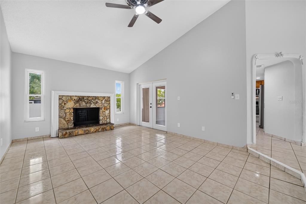 A living room with tile flooring, a stone fireplace, and a vaulted ceiling — 1224 ANDES DR, WINTER SPRINGS, FL