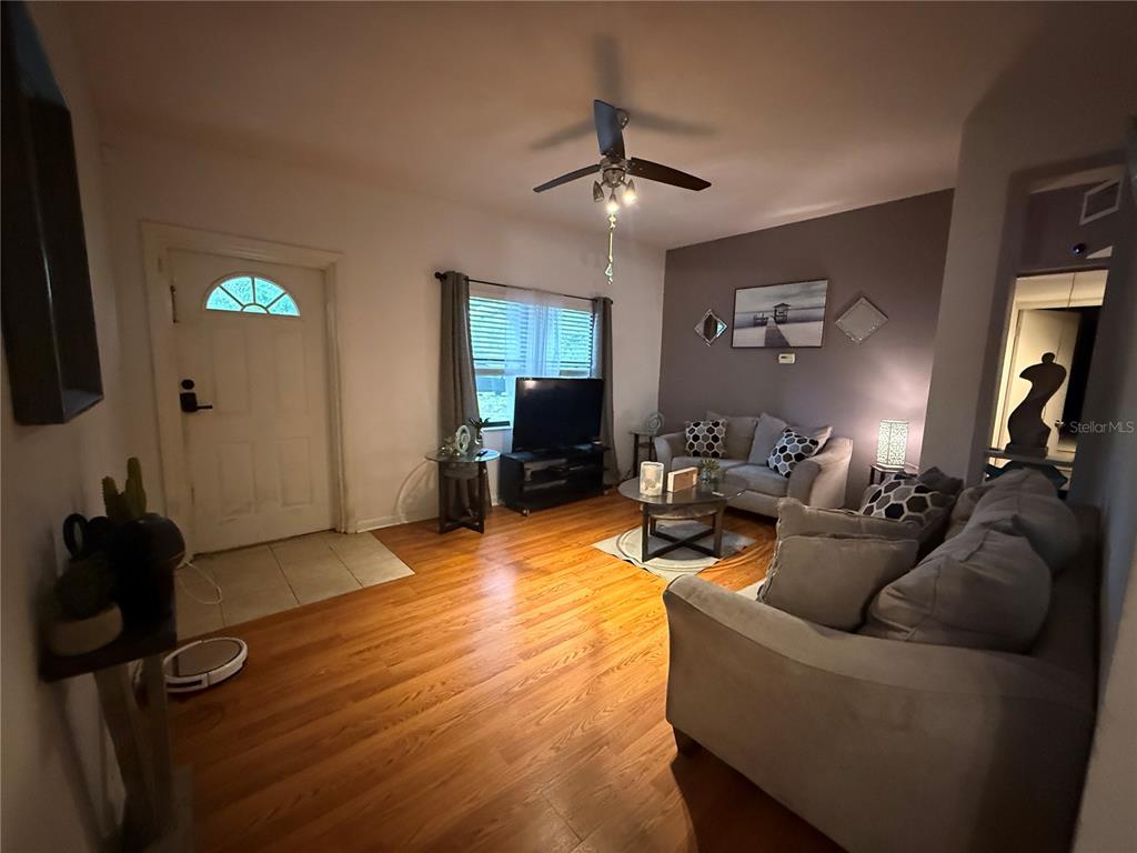 A living room features hardwood floors, a ceiling fan, and two gray sofas — 1435 TRIANGLE DRIVE, MOUNT DORA, FL