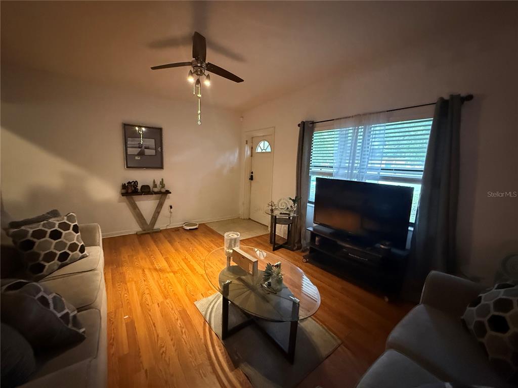 A living room features hardwood floors, a ceiling fan, a television, and two sofas — 1435 TRIANGLE DRIVE, MOUNT DORA, FL