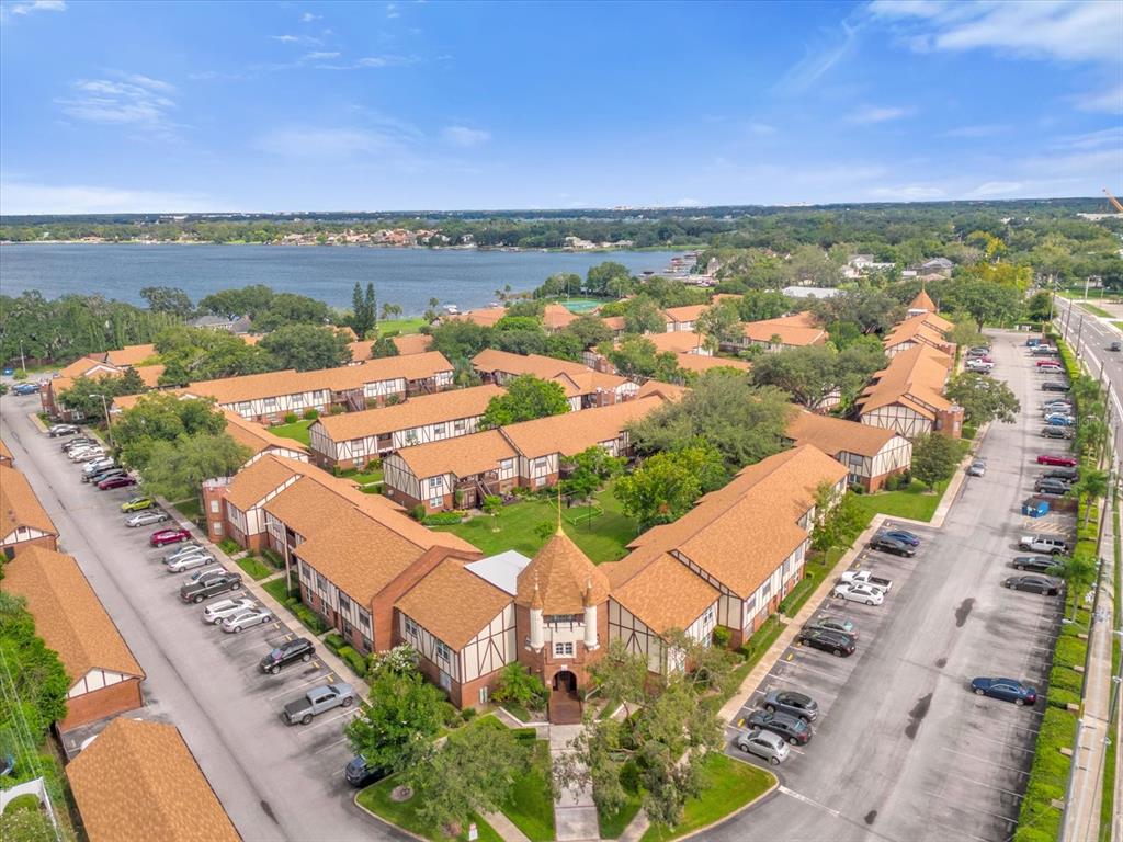 A brick building entrance features a wooden walkway, hanging lanterns, and a brown front door — 5419 HANSEL AVENUE UNIT K12, ORLANDO, FL