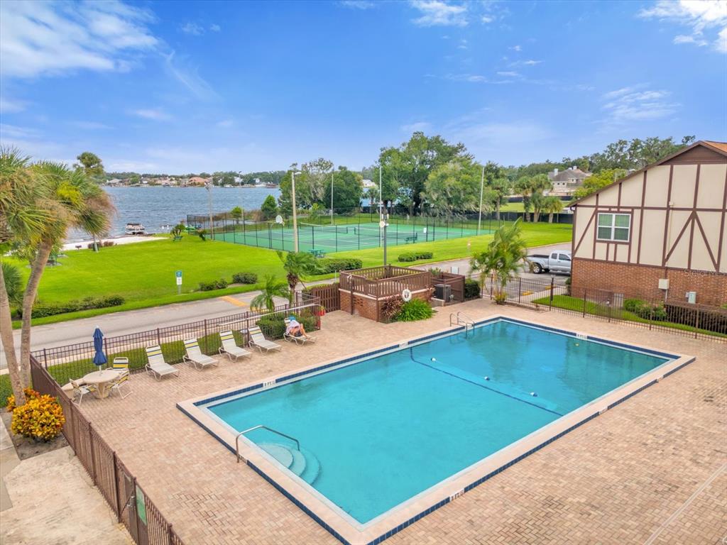 An aerial view shows a waterfront apartment complex with a tennis court and boat docks — 5419 HANSEL AVENUE UNIT K12, ORLANDO, FL