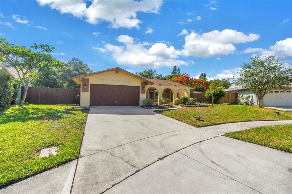 A single-story house with a two-car garage, arched entryway, and a concrete driveway — 10657 DEL PRADO DRIVE E, LARGO, FL