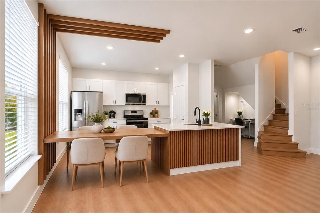 A modern kitchen with white cabinets, wood-slat accents, and a staircase leading to an upper level — 10359 LAKE DISTRICT LANE UNIT 58B, ORLANDO, FL