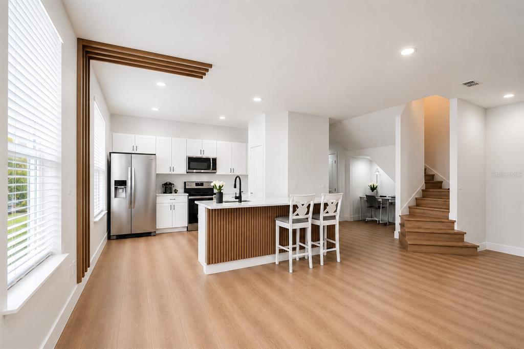 A modern living room features light wood flooring, a sectional sofa, and a wall-mounted television — 10359 LAKE DISTRICT LANE UNIT 58B, ORLANDO, FL