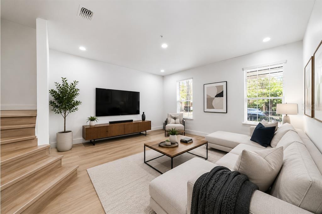 An empty room with light wood-look flooring, white walls, recessed lighting, and a wooden staircase — 10359 LAKE DISTRICT LANE UNIT 58B, ORLANDO, FL