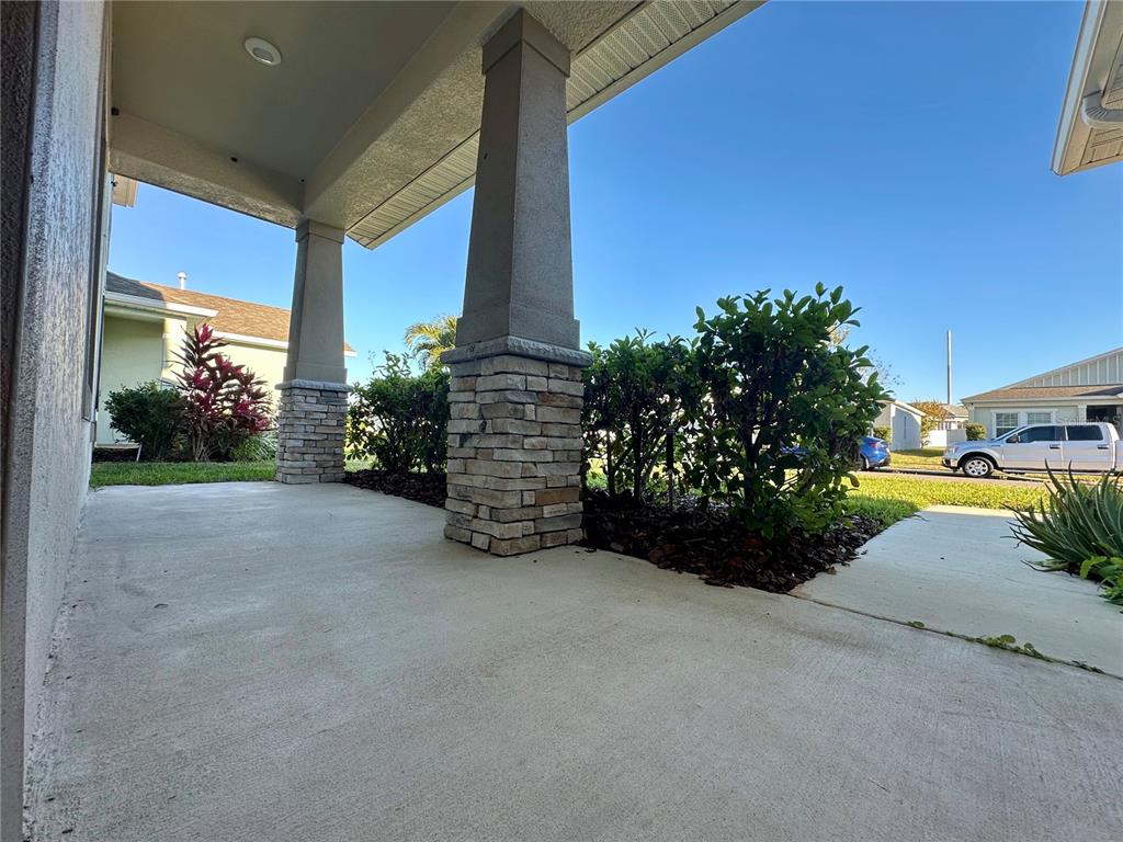 A covered concrete porch features two stone-based columns and a view of the front yard — 177 BELLA VERANO WAY, DAVENPORT, FL