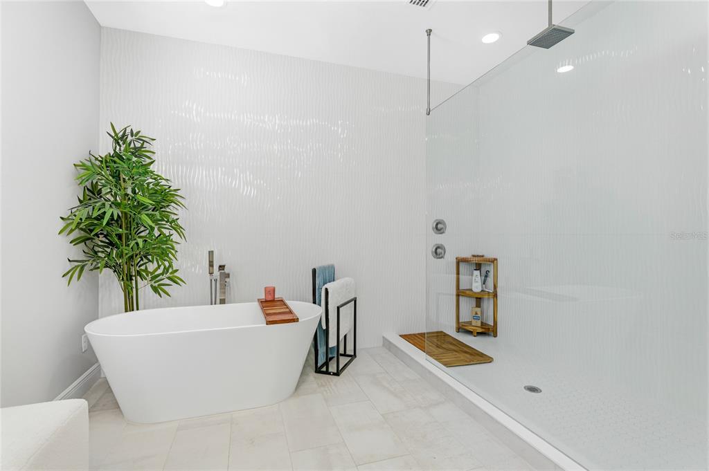 A modern bathroom features a freestanding white tub, a glass-enclosed shower, and textured white walls — 1735 LAKE VERONA CIRCLE, BRADENTON, FL
