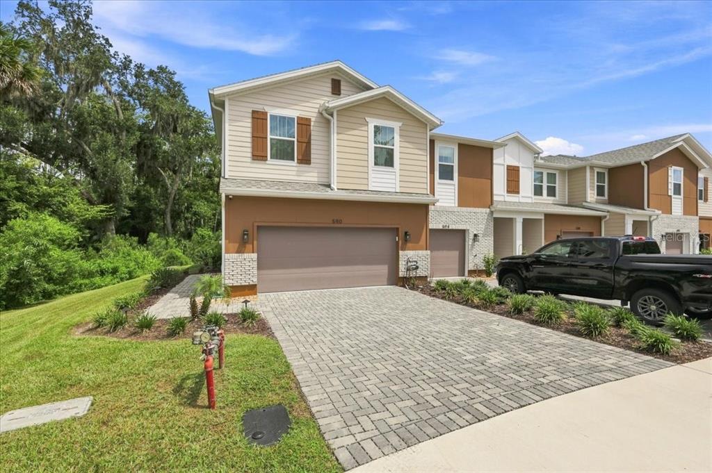 A two-story townhouse with a paved driveway, a two-car garage, and tan siding — 590 SOUTHERN EDGE WAY, SANFORD, FL