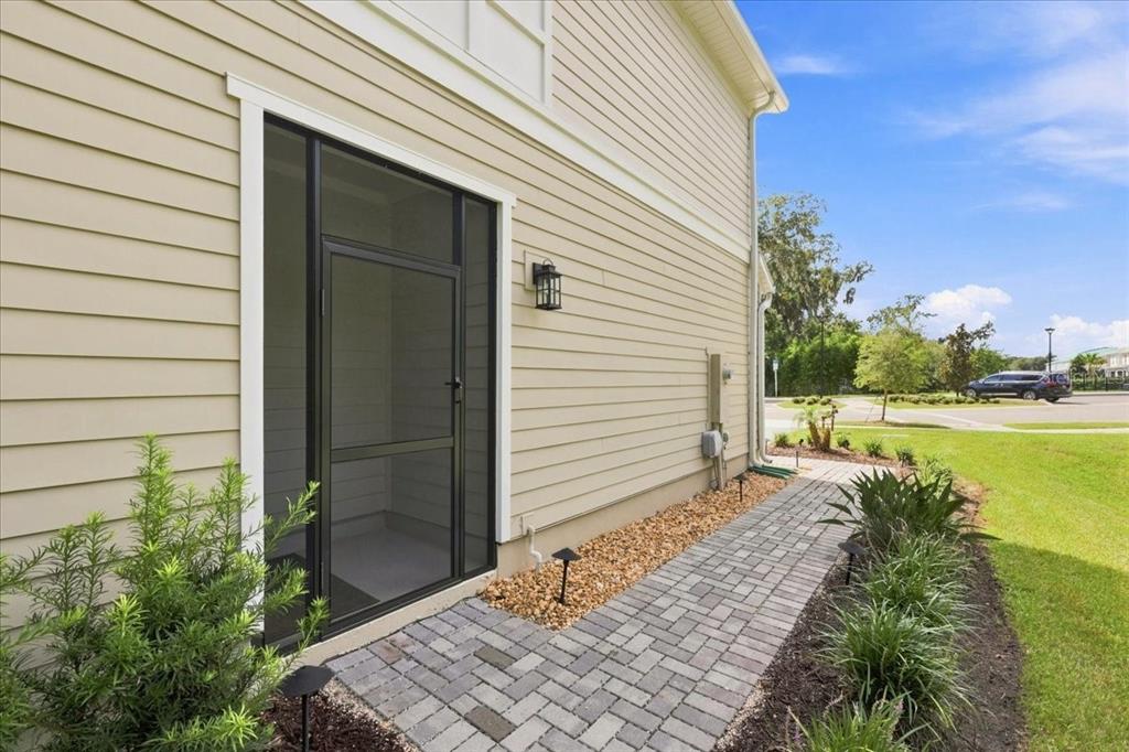 A beige house exterior features a screened door, a stone walkway, and a gravel garden bed — 590 SOUTHERN EDGE WAY, SANFORD, FL