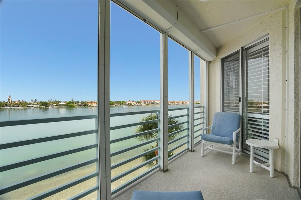 An aerial view shows a multi-story apartment building situated along a waterfront with parking areas — 7984 SAILBOAT KEY BOULEVARD S UNIT 306, SOUTH PASADENA, FL