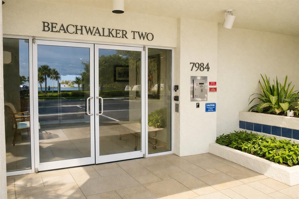 A multi-story apartment building features covered parking, palm trees, and a speed limit sign — 7984 SAILBOAT KEY BOULEVARD S UNIT 306, SOUTH PASADENA, FL