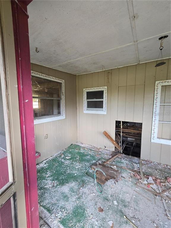 A dilapidated porch with wood-paneled walls, a damaged floor, and exposed structural framing — 17208 MERCURY ROAD, ORLANDO, FL