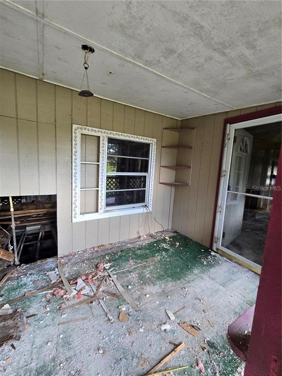 A dilapidated porch features exposed subflooring, a window with decorative trim, and open wall shelving — 17208 MERCURY ROAD, ORLANDO, FL