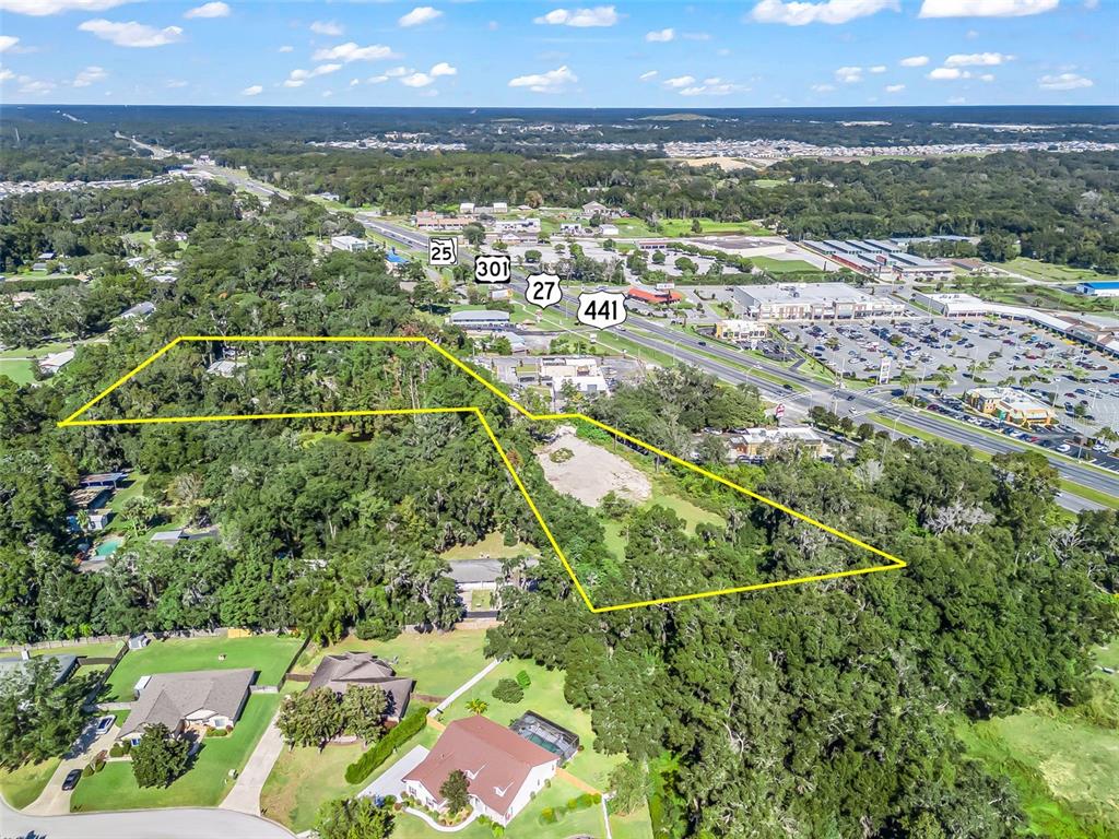 An aerial view shows a large, wooded plot of land outlined in yellow near a highway — 10366 S US HIGHWAY 441, BELLEVIEW, FL