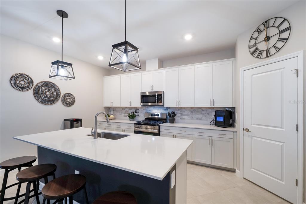 An open-concept living and dining area features a stone accent wall and a kitchen island — 15041 SERENE SHORES LOOP, BRADENTON, FL