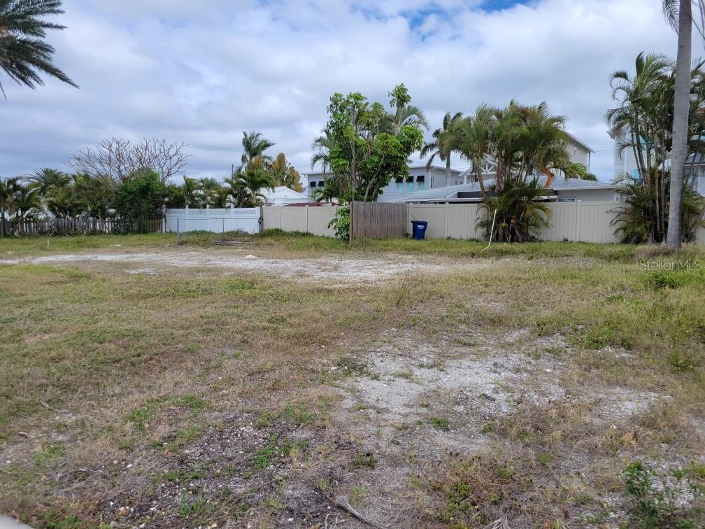 A vacant, grassy lot with patches of sand is enclosed by a white vinyl fence — 235 145TH AVENUE E, MADEIRA BEACH, FL